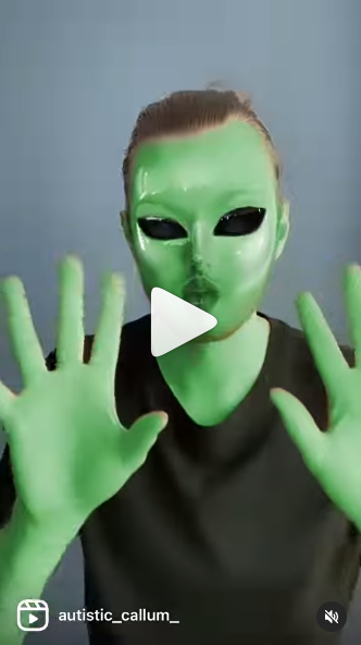 Person with green skin wearing green mask and black shirt and dancing.